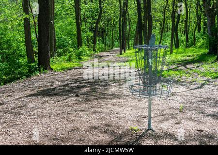 A disc golf goal waits for players on a wooded fairway. Stock Photo