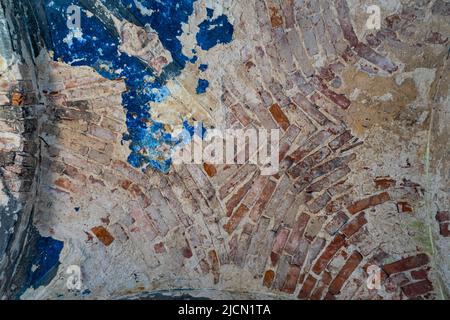 Ancient ceiling in a ruined red brick building with ragged blue plaster Stock Photo
