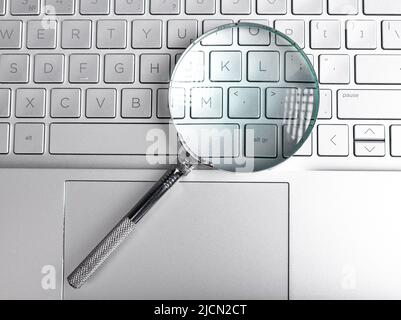Magnifying lens over laptops keyboard. Seo and search concept. High quality photo Stock Photo