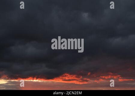 Thunderclouds with breaking rays sun at sunset Stock Photo