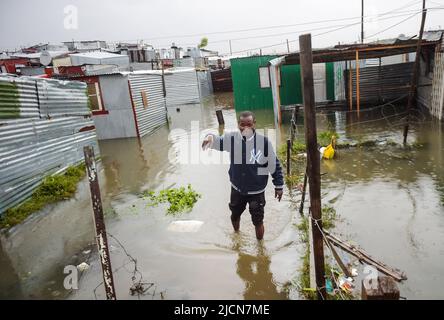 Cape Town, South Africa. 14th June, 2022. A man wades in a flooded informal settlement area in Cape Town, South Africa, on June 14, 2022. A cold front caused heavy rainfall in Cape Town on Monday and Tuesday. Credit: Xabiso Mkhabela/Xinhua/Alamy Live News Stock Photo