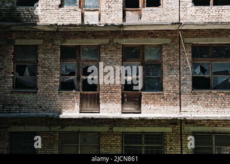 The wall of an old abandoned brick building with broken windows. Stock Photo