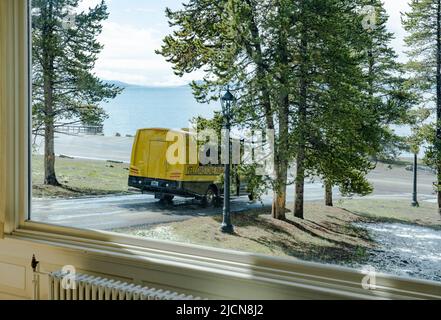 Yellowstone Park tour bus  passenger business in front of Lake hotel leaving with travelers who are sightseeing.Yellowstone Lake is in the distance. Stock Photo