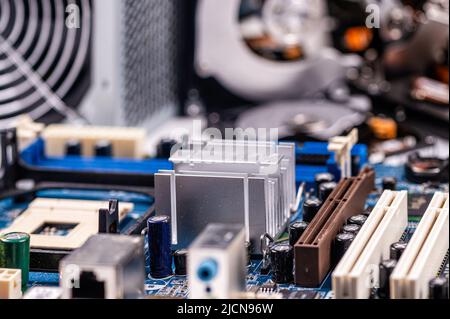 fragment of computer circuit board with components on the background of defocused power supply fans Stock Photo