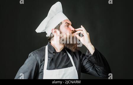 Professional chef shows sign for delicious. Male cook, baker in uniform with taste approval gesture. Stock Photo