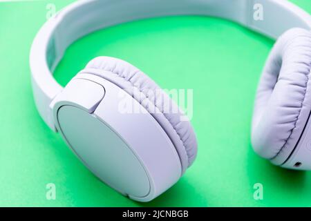 Close-up wireless headphones isolated on a green background. Stock Photo