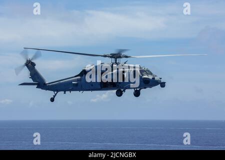 PHILIPPINE SEA (June 12, 2022) An MH-60S Sea Hawk helicopter, assigned to the “Chargers” of Helicopter Sea Combat Squadron (HSC) 14, flies over the Philippine Sea during Valiant Shield 2022 (VS22). VS22 is a U.S.-only, biennial field training exercise (FTX) focused on integration of joint training in a multi-domain environment. This training builds real-world proficiency in sustaining joint forces through detecting, locating, tracking, and engaging units at sea, in the air, on land, and in cyberspace in response to a range of mission areas. (U.S. Navy photo by Mass Communication Specialist Sea Stock Photo