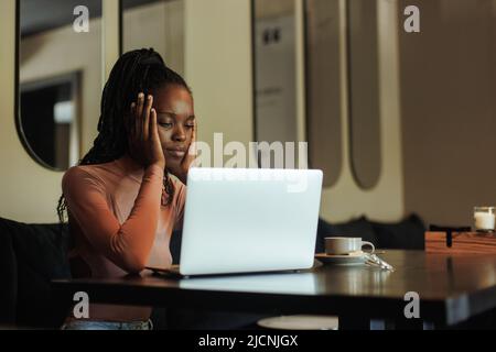 Anxious, tired and angry multiracial afro american business woman freelance work using laptop at cafe, creative office Stock Photo