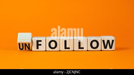 Follow or unfollow symbol. Turned wooden cubes and changed concept words Follow to Unfollow. Beautiful orange table orange background. Business and fo Stock Photo