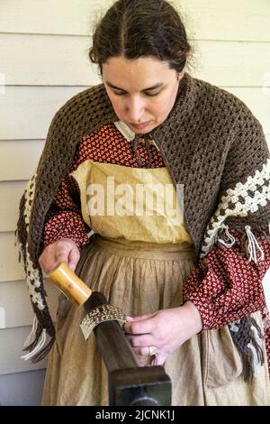 woman working with tin while wearing authintic clothing from the 1850s at Fort Nisqually Living Museum in Tacoma, Washington Stock Photo