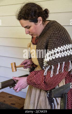 woman working with tin while wearing authintic clothing from the 1850s at Fort Nisqually Living Museum in Tacoma, Washington Stock Photo