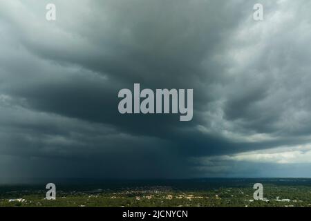 Landscape of dark ominous clouds forming on stormy sky before heavy thunderstorm over rural town area Stock Photo