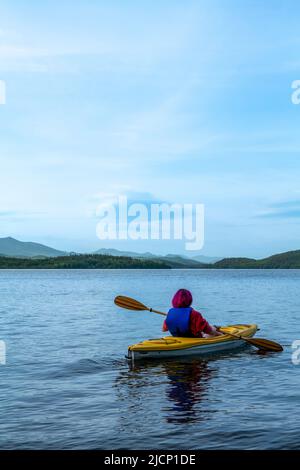 Woman kayaking. Rear view of young woman splashing water while kayaking on river Stock Photo