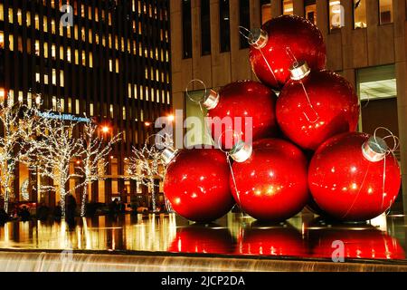 Large red Christmas balls are stacked in a pyramid shape on a fountain in Manhattan's Rockefeller Center, part of the holiday season in New York City Stock Photo