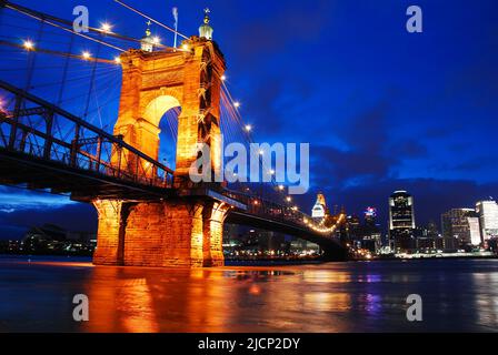 The lights of the Cincinnati skyline and the Roebling Bridge are reflected in the waters of the Ohio River at night Stock Photo