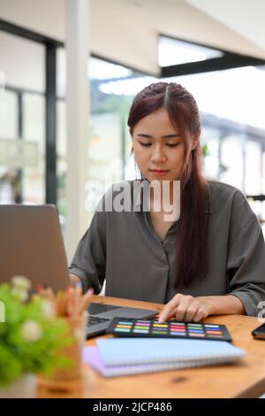 Portrait, Beautiful millennial Asian female graphic designer concentrated working on the project at her office desk. Stock Photo