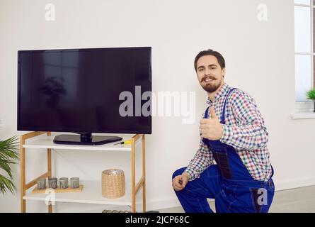 Happy technician showing thumbs up after he has repaired or installed television set Stock Photo