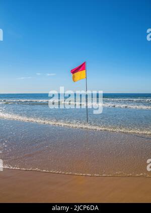 Red and yellow surf lifesaving flag on Australian beach Stock Photo