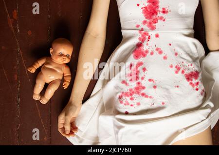 A murdered and tortured Ukrainian woman in a white dress and bloodstains lies on the floor of the house, a protest action by Ukrainian women, protecti Stock Photo