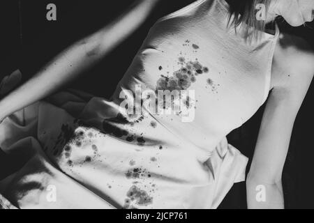 A murdered and tortured Ukrainian woman in a white dress and bloodstains lies on the floor of the house, a protest action by Ukrainian women, protecti Stock Photo