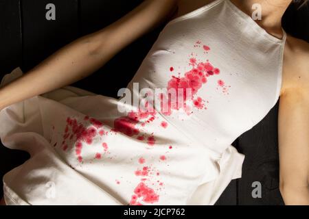 A murdered and tortured Ukrainian woman in a white dress and bloodstains lies on the floor of the house, a protest action by Ukrainian women, protecti Stock Photo