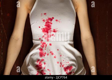 A murdered and tortured Ukrainian woman in a white dress and bloodstains lies on the floor of the house, a protest action by Ukrainian women, protecti Stock Photo