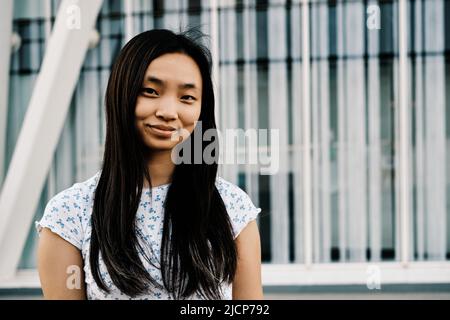 Portrait of a young woman looking at the camera and smiles while posing outdoors. Stock Photo