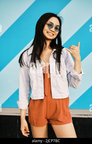 Young woman with sunglasses smiling at the camera while posing outdoors. Stock Photo