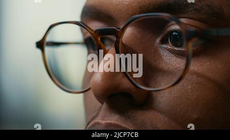 Closeup portrait of african american database developer with glasses working focused looking at computer screen while typing. Focus on moving eyes of software developer writing ai code. Stock Photo