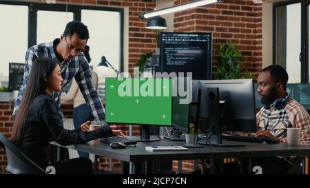 Two software developers analyzing source code looking at green screen chroma key mockup with coworker sitting at desk writing algorithm. Software developers working on artificial intelligence project. Stock Photo