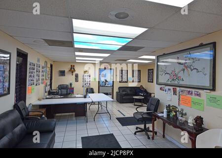 A man using his cell phone sits in the waiting area of an auto repair shop Stock Photo