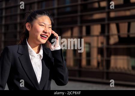smiling businesswoman walking talking by phone Stock Photo