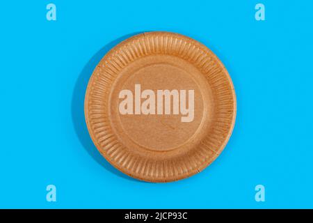Disposable paper biodegradable plate on a blue background. Top view. Flat lay composition. Stock Photo