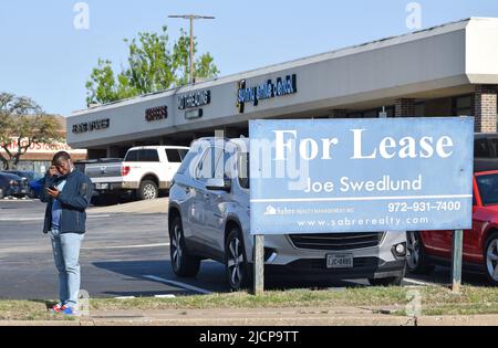 African American man looking at his phone, waiting for a bus, standing next to a For Lease sign Stock Photo