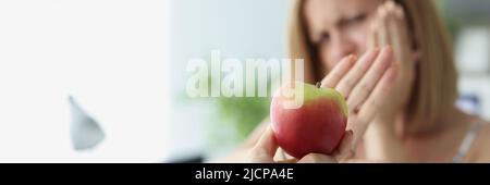 Blonde woman refuse to eat apple because of teeth pain Stock Photo