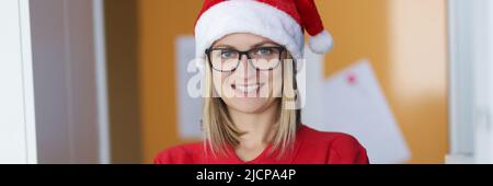 Happy blonde lady courier in red shirt and santa claus hat Stock Photo