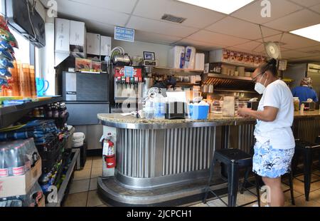 A hungry customer, wearing a mask, waits for her food at the Record Grill in downtown Dallas, Texas Stock Photo