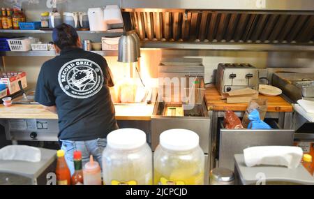 Interior of the Record Grill, a small hole in the wall restaurant, in downtown Dallas, Texas where a cook / clerk is hard at work on pick up orders Stock Photo