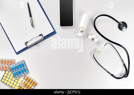 Stethoscope in the office of doctors.Top view of doctor's desk table, blank paper on clipboard with pen. Copy space. Designer's blank Stock Photo