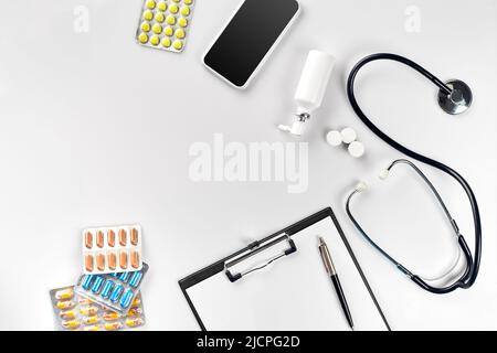Stethoscope in the office of doctors.Top view of doctor's desk table, blank paper on clipboard with pen. Copy space. Designer's blank Stock Photo