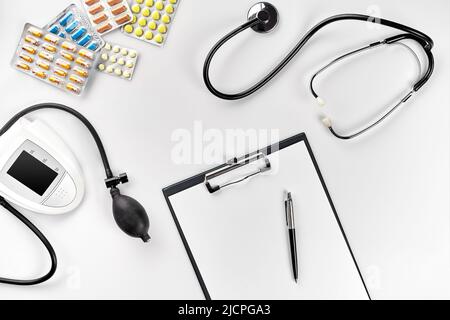 Stethoscope in the office of doctors.Top view of doctor's desk table, blank paper on clipboard with pen. Copy space. Designer's blank Stock Photo