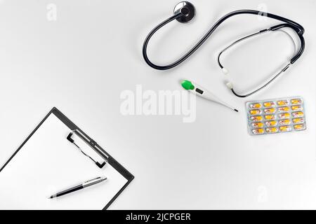 Stethoscope in the office of doctors.Top view of doctor's desk table, blank paper on clipboard with pen. Copy space. Designer's blank Stock Photo