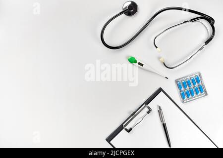 Stethoscope in the office of doctors.Top view of doctor's desk table, blank paper on clipboard with pen. Copy space. Designer's blank Stock Photo