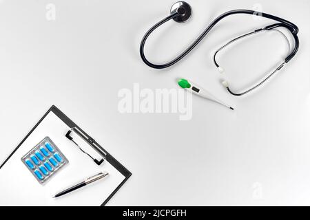 Stethoscope in the office of doctors.Top view of doctor's desk table, blank paper on clipboard with pen. Copy space. Designer's blank Stock Photo