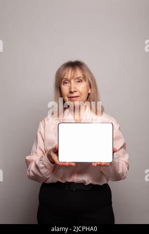 Senior woman showing tablet with white empty display Stock Photo
