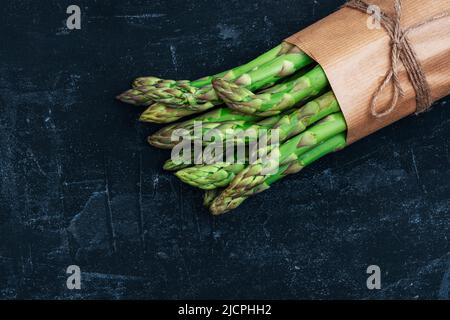 Fresh green asparagus on black table. Healthy vegan food concept. Top view, flat lay. Stock Photo