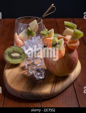 Yummy fruit skewers with apple, mandarin and kiwi on wooden table Stock Photo