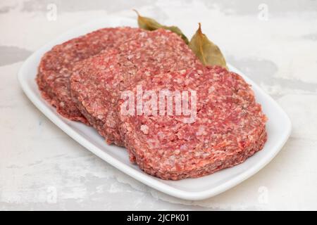 fresh raw minced meat on white dish with bay leaf Stock Photo