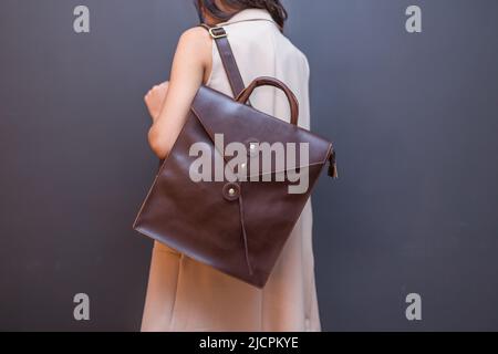 Back of woman with brown leather backpack. Unisex bag for sale. Stock Photo