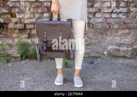Gray canvas backpack in the hand on a woman. Unisex bag for sale. Stock Photo